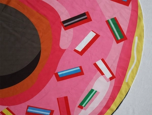 Close-up of circular microfiber beach towel featuring vibrant pink donut print texture