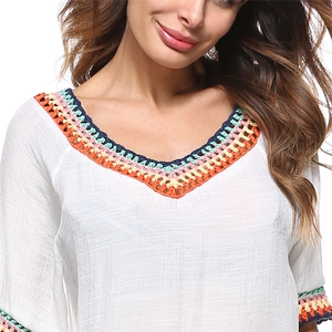 Détails du décolleté et des manches crochetés à la main sur une robe de plage blanche