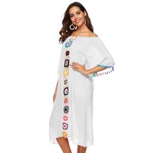 Détails d'appliques florales au crochet et pompons sur une robe de plage blanche