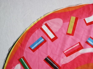 Detail of round pizza donut beach shawl with vibrant pink glaze print and white stitching