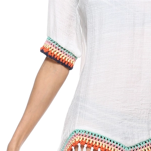 Détail de la broderie crochetée colorée et des glands blancs sur la manche du vêtement