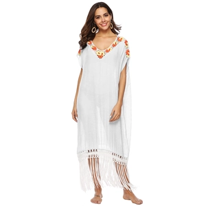 Detailed view of colorful crochet floral embroidery on a white bohemian beach kaftan neck