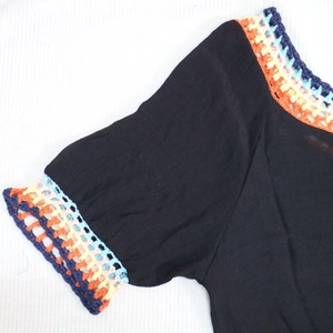 Détail de l'encolure et des manches en patchwork de crochet coloré sur un haut de plage noir