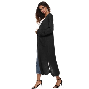 Detail of long black knit cardigan showing side slits and large pockets on fabric