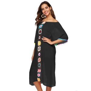 Détail de robe noire bohème avec dentelle florale au crochet et garniture de pompons