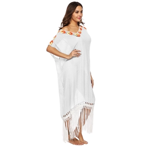Detail of white bohemian beach cover-up featuring yellow crochet embroidery and fringe