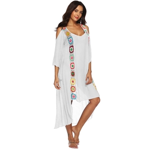 Detailed close-up of colorful crochet knit patterns on a white bohemian beach cover-up dress