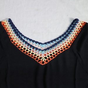 Détail du col en V avec bordure en dentelle crochetée colorée sur haut de plage noir