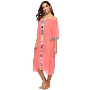 Détail de broderie au crochet colorée et de mini glands à pompons sur la robe de plage corail
