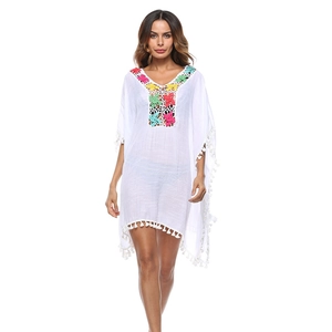 Dettaglio copricostume bianco boho con ricamo floreale all'uncinetto su scollo V e frange