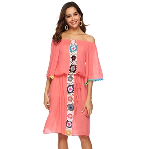 Détail d'une robe rose à épaules dénudées avec fleurs au crochet et pompons colorés