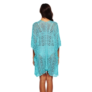 Detail of bright blue crochet beach cover-up with intricate hollow patterns and fringe