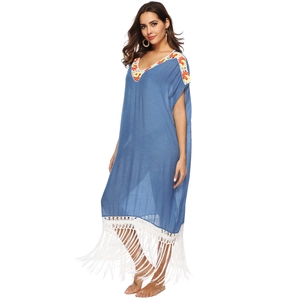 Detailed view of orange floral embroidery and white fringe on a blue V-neck beach kaftan