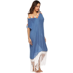 Detailed close-up of bohemian crochet trim and long white tassels on a blue beach dress