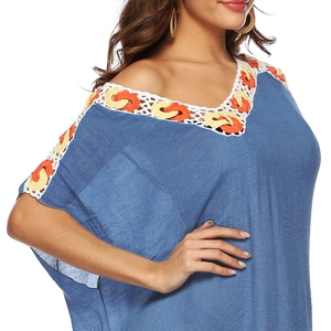 Close-up of blue beach cover-up featuring colorful crochet embroidery and V-neckline