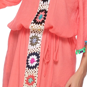 Détail de robe de plage corail avec bande au crochet fleurie, cordon et pompons