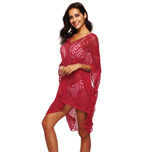 Detail of red crochet knit beach cover-up with hollow floral patterns and wavy hemline