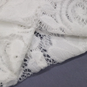 Gros plan du bandeau en dentelle blanche montrant des motifs floraux ajourés