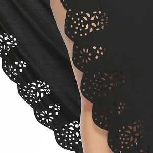 Detail of scalloped laser-cut hem with floral lace patterns on a black beach dress