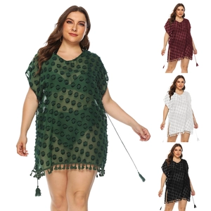 Detail of plus size chiffon beach dress showing pom-pom trim and textured dots on fabric
