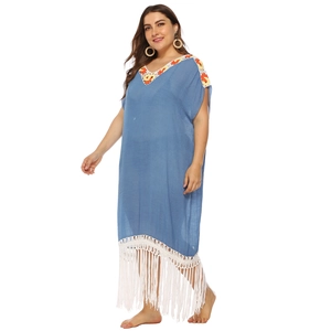 Detailed view of bohemian blue dress with ethnic embroidery and long white tassels