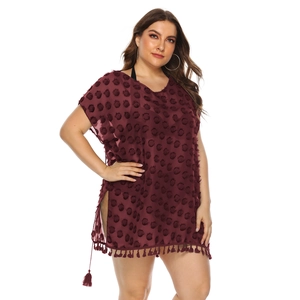 Detail view of burgundy chiffon beach dress with pom-pom texture and tassel hemline