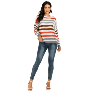 Détail d'un pull en maille rayé multicolore avec un jean slim bleu foncé ajusté