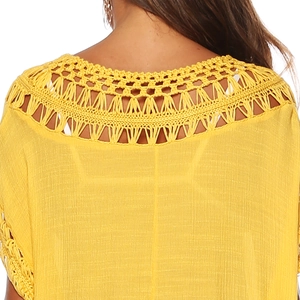 Gros plan sur le décolleté au crochet jaune vif avec texture évidée de la robe de plage