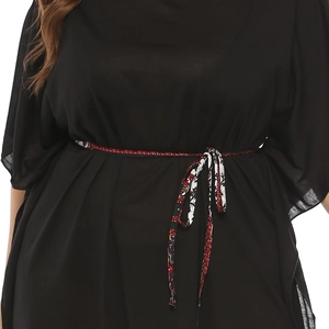 Détail d'une ceinture à imprimé ethnique sur une robe noire ample avec manches cloche