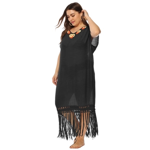 Detail of black boho beach cover-up with orange floral embroidery and woven fringe hemline