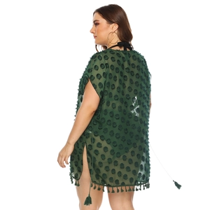 Detail of dark green chiffon beach dress with pom-poms, side slits and tassel hem
