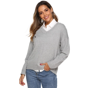 Close-up of a light grey V-neck knitted sweater layered with a white shirt and jeans