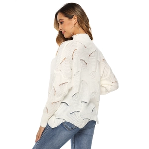 Detail of white knit sweater showing textured hollow wave pattern and high neck design