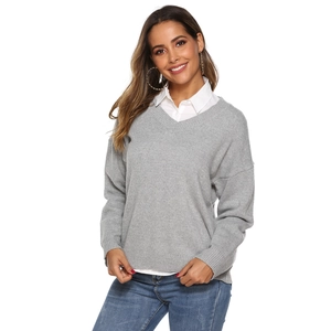 Close-up of V-neck grey knit sweater layered over a white shirt with collar detail