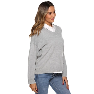 Detail of light gray V-neck knitted sweater paired with white collared shirt and jeans
