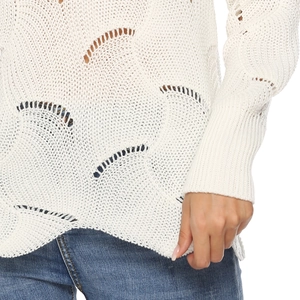 Close-up of white hollow knit sweater showing intricate wavy crochet pattern and texture