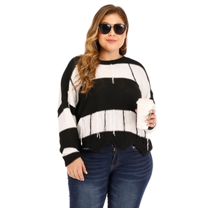Detail of black and white striped knit sweater featuring hanging tassel fringe at the hem