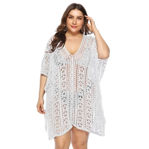 Detail of white crochet knit cover-up showing intricate hollow-out patterns and V-neckline