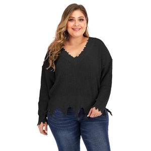 Detail view of deep V-neckline and distressed frayed edges on a thick black knitted sweater