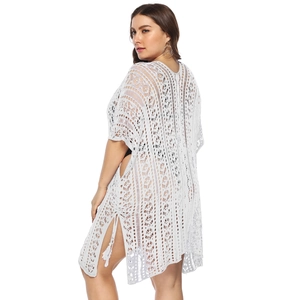 Detailed side view of white crochet beach cover-up featuring side slit and tassel details
