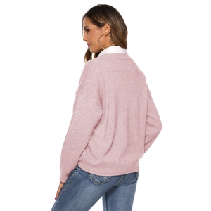 Detail of pink knitted sweater with ribbed cuffs and collar showing a layered look