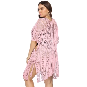 Detail of pink crochet beach cover-up featuring geometric knit patterns and tassel side ties