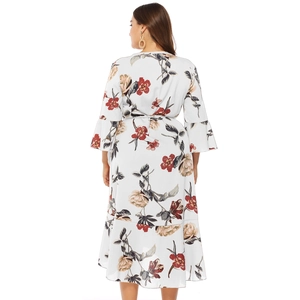 Detail of floral print dress featuring layered ruffle hem and bell sleeves on white fabric