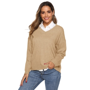 Detail of khaki V-neck knitted sweater over white collared shirt and blue denim jeans