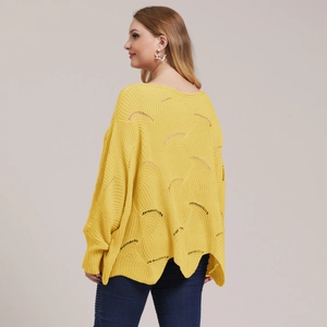Detail of yellow loose knit sweater featuring hollow wavy patterns and scalloped hemline