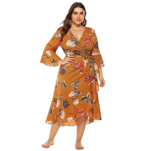 Close-up of mustard floral plus size wrap dress with ruffle hem and tie waist detail