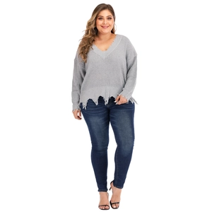 Detail of distressed hem and V-neckline on a light grey chunky knit oversized sweater