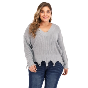 Close-up of grey V-neck knit sweater featuring distressed ripped edges and fringe trim detail