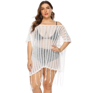 Detailed close-up of white crochet knit beach cover-up with tassel fringe hem design