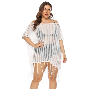 Detail of white crochet knit cover-up showing hollow texture and long fringe hem
